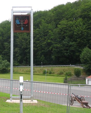 Vogelstange mit Schützenvogel im Vordergrund eines ländlichen Gebiets.