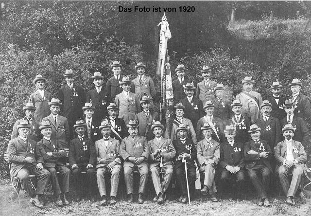 Gruppe von Männern in uniformierten Kleidern, posierend vor einer Flagge, 1923.