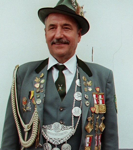 Mann in traditioneller Tracht mit Abzeichen und einem Hut.